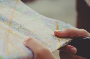 relocate. A pair of hands holds a paper map to indicate researching your rental property's location