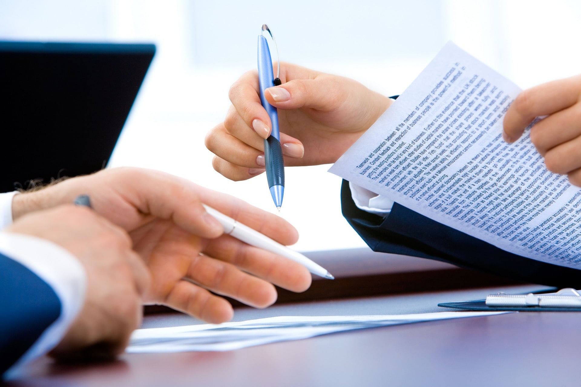 A property manager holds a rental policy agreement and pen to hand to a potential tenant to review.