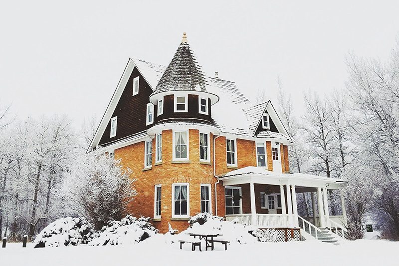 A massive house covered in snow during the winter.