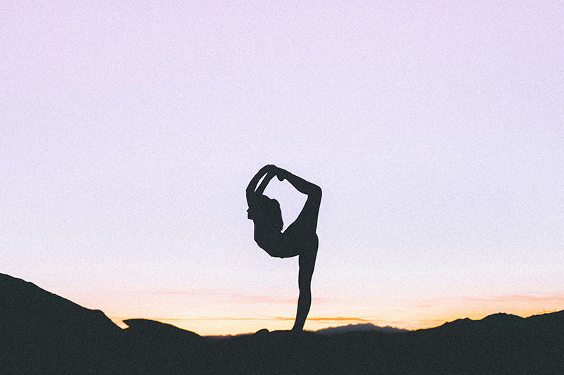 A woman doing King of the Dancers pose in yoga (Natarajasana), named after Shiva Nataraja, King of the Dance.