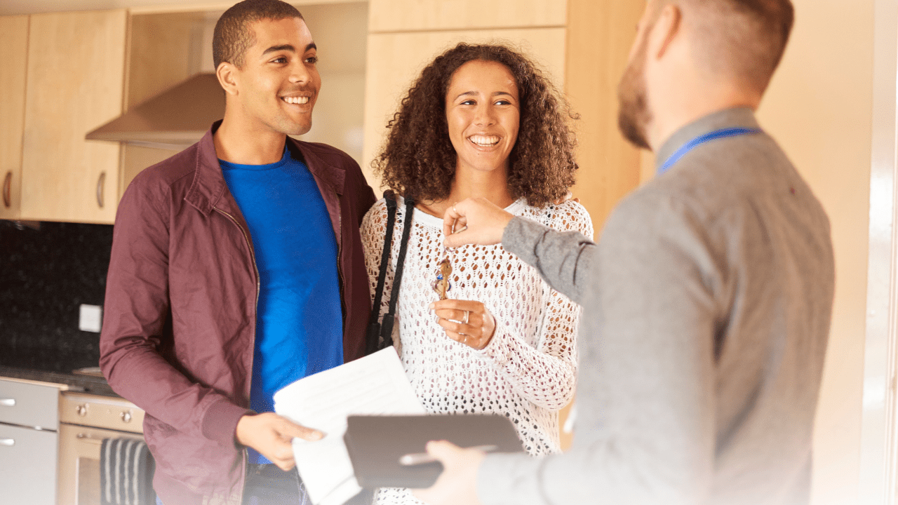 A young couple happily takes the keys to their new rental property as the new tenants