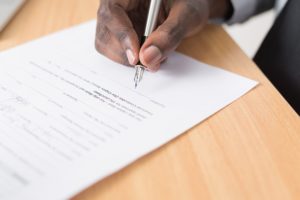 A tenant holds a pen and signs an application form for a rental property