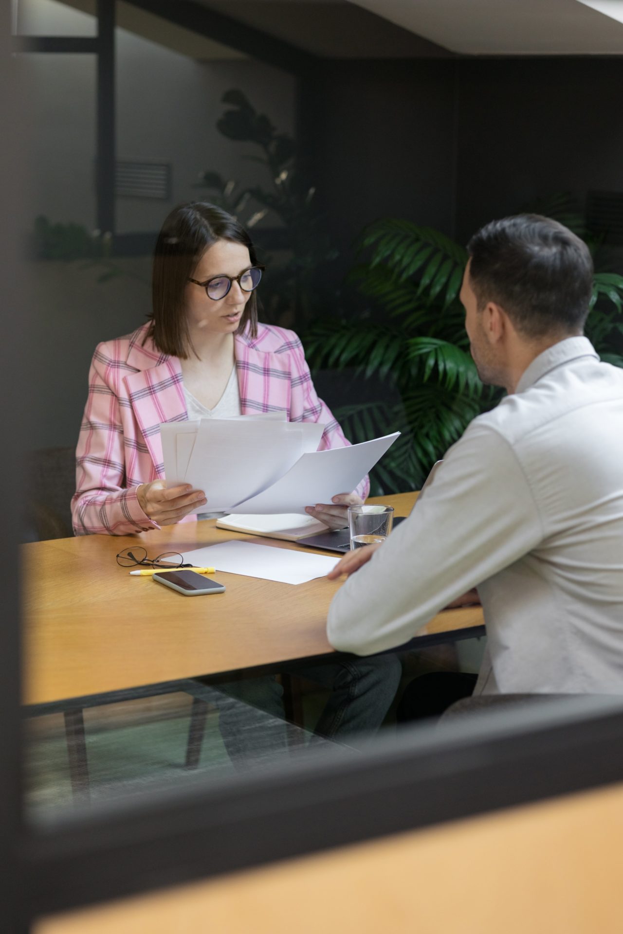 A woman in a pink blazer reviews rental applications with a man in a white shirt in an office as they try to Find New Tenant for rental properties.