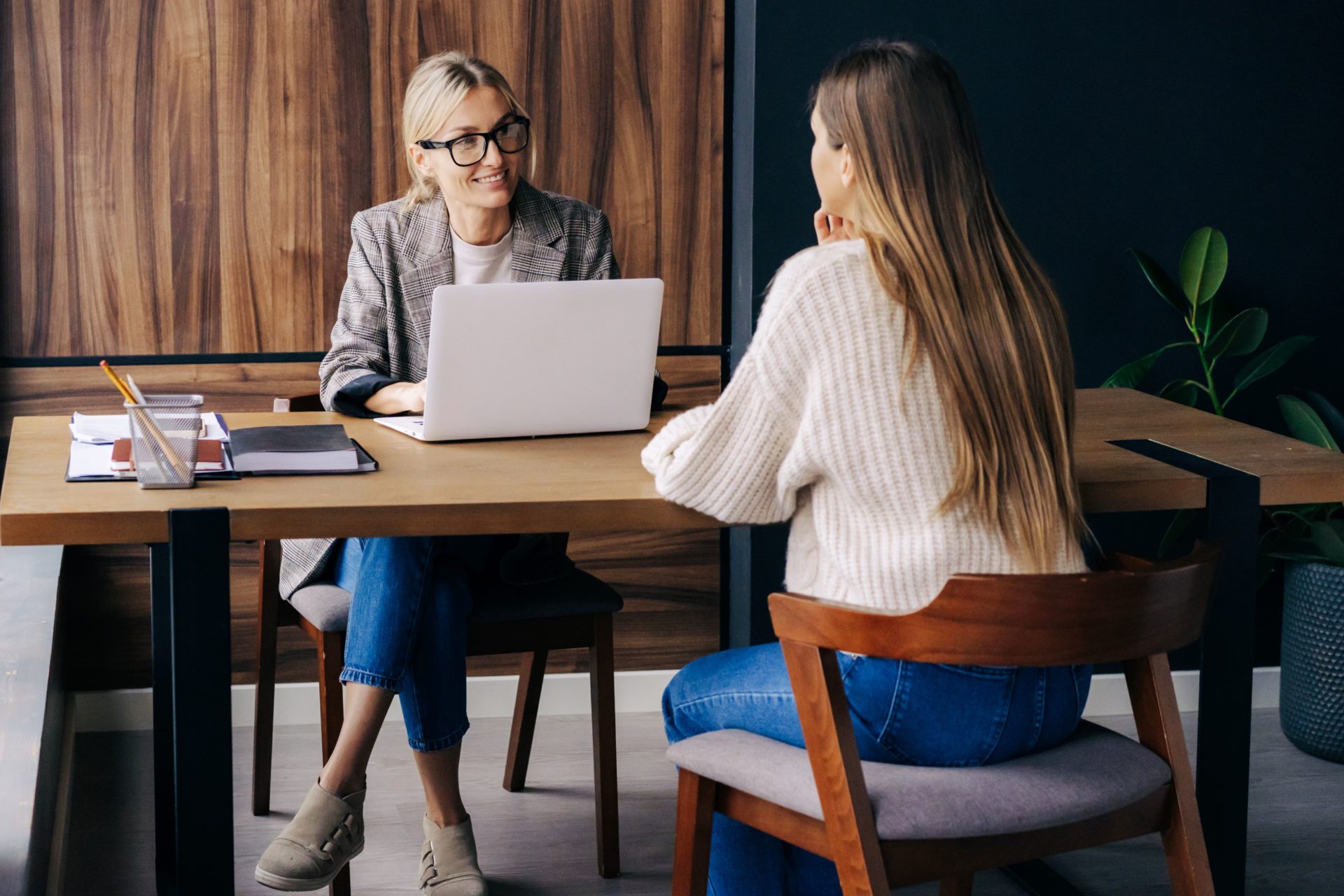 A woman in a blazer and jacket sits with another woman in a white sweater at a table while using a white laptop as she interviews the other woman to potentially become a new tenant. A property manager can help you find a new tenant, navigate Canadian rental laws and more. Find New Tenant Vantage West Property Management.