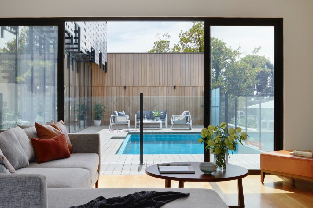 brown sofa near glass window with swimming pool