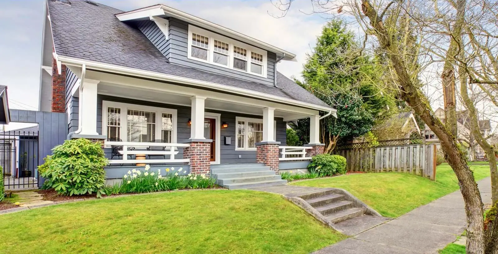 A beautiful traditional style Kelowna home with a green lawn and tidy gardens on a sunny day, a rental home managed by Vantage West Property Management Kelowna.