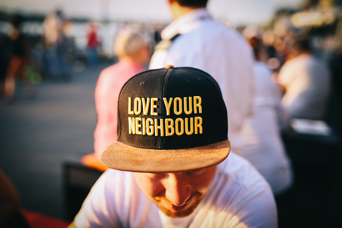 A dude wearing a hat that says "love your neighbour"